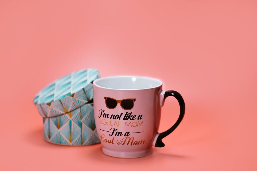 Chic mug with humorous text for mom, paired with an elegant gift box on a pink backdrop.